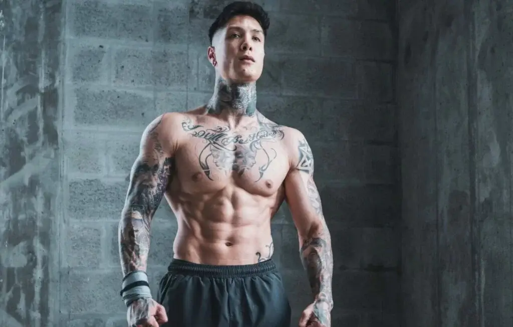 Chris Heria posando de pie mostrando su físico con el torso desnudo.