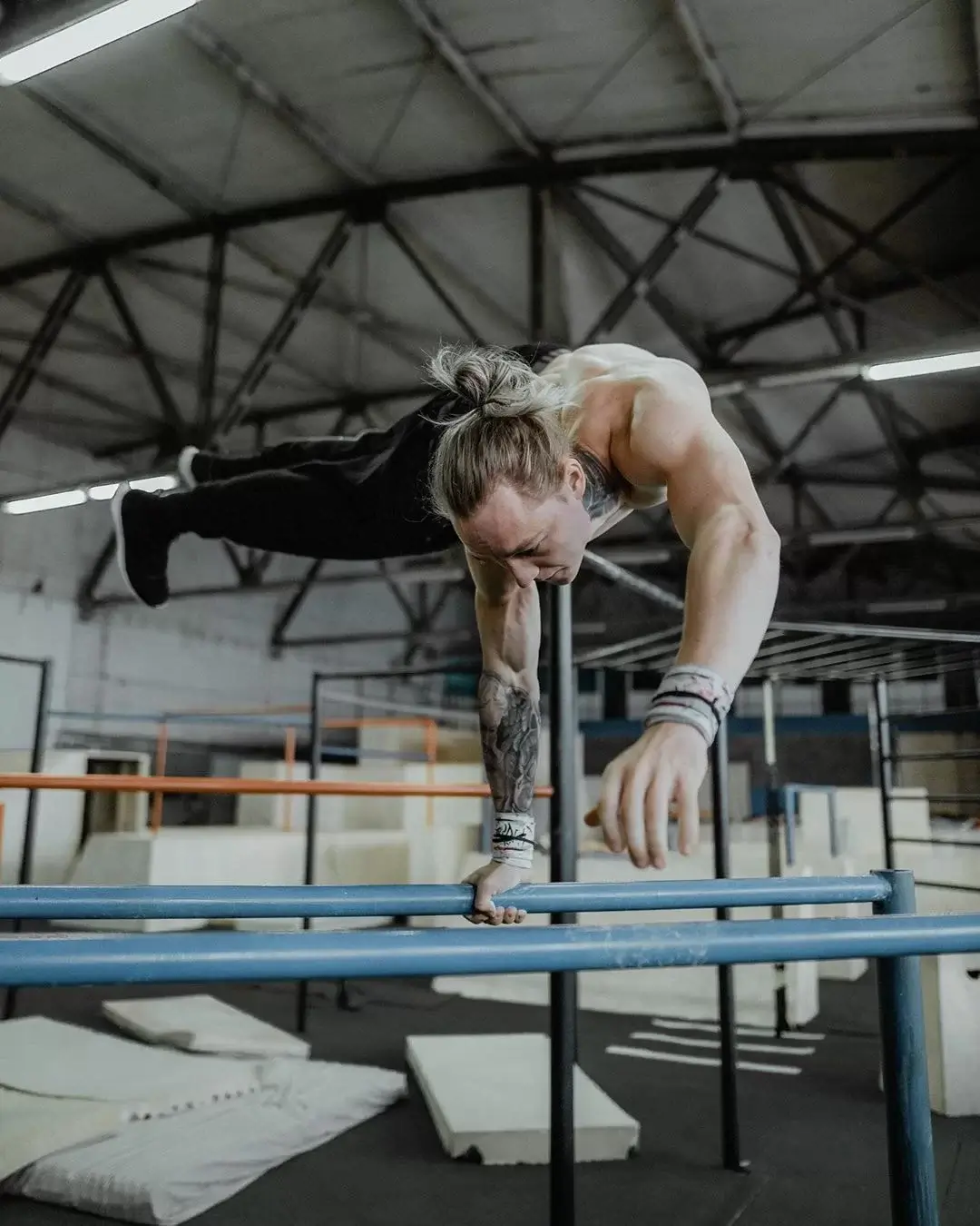 Daniels Laizans haciendo un planche a un brazo en paralelas