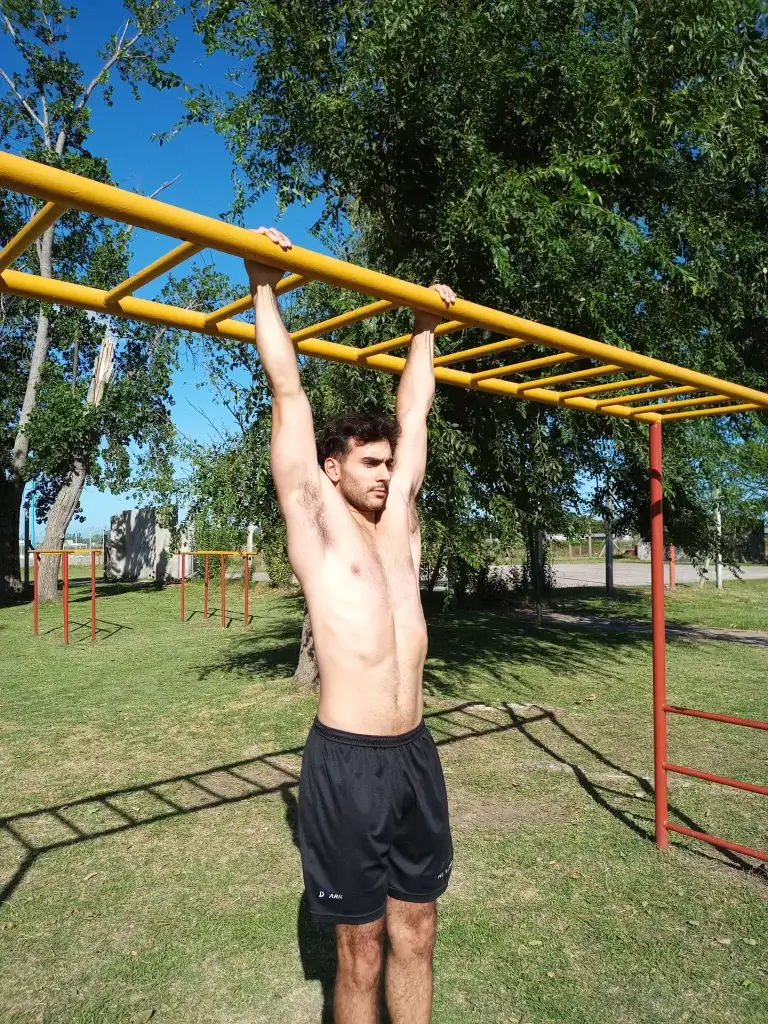lucas galdeano colgado de manos en una pasa manos color amarillo