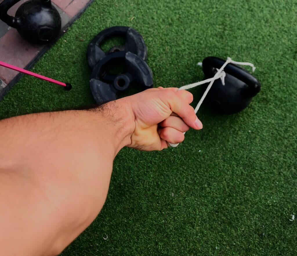 brazo extendido agarrando una mancuerna rusa de una soga, ejercicio para antebrazo