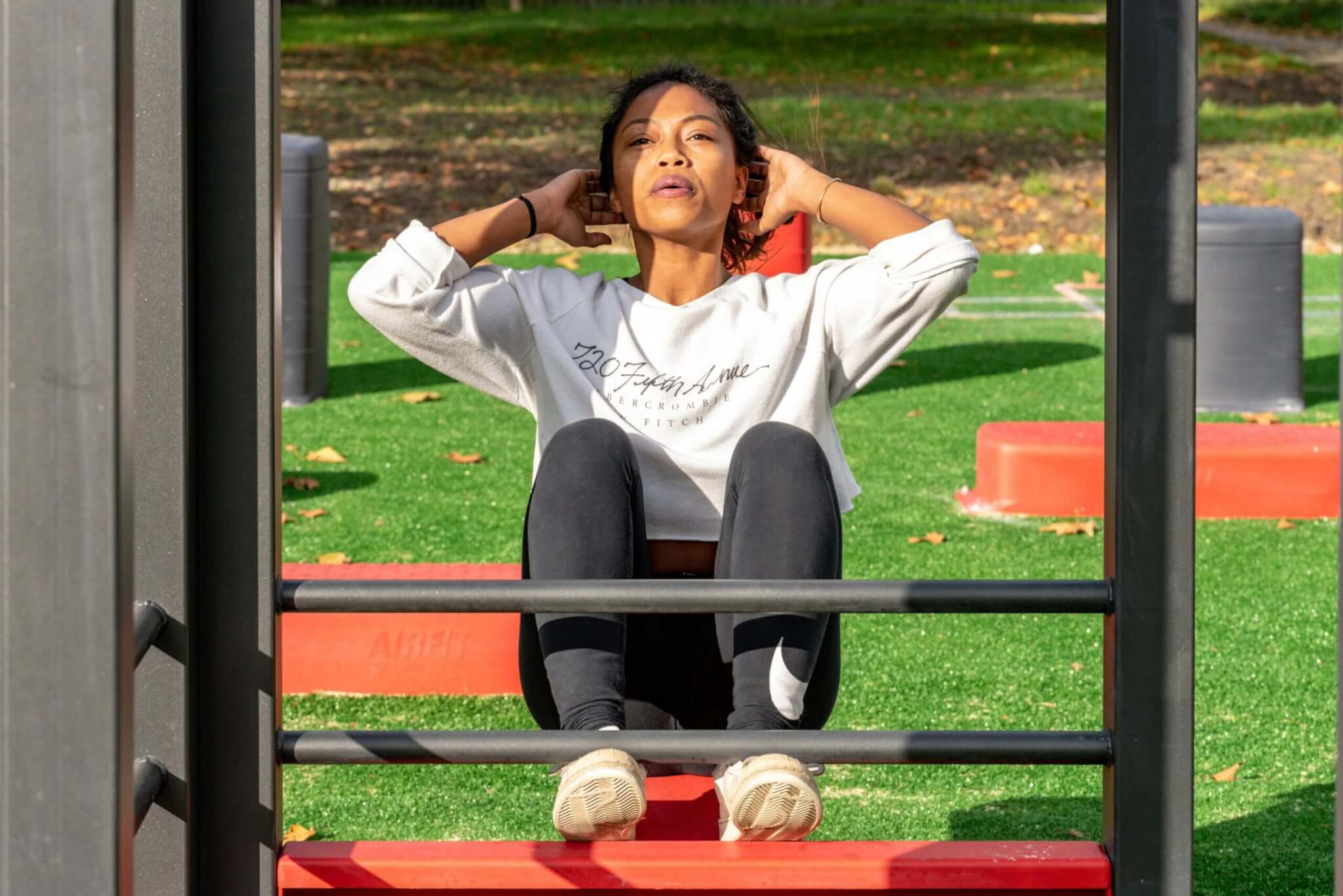 Mujer haciendo una rutina de abdominales en un parque de calistenia